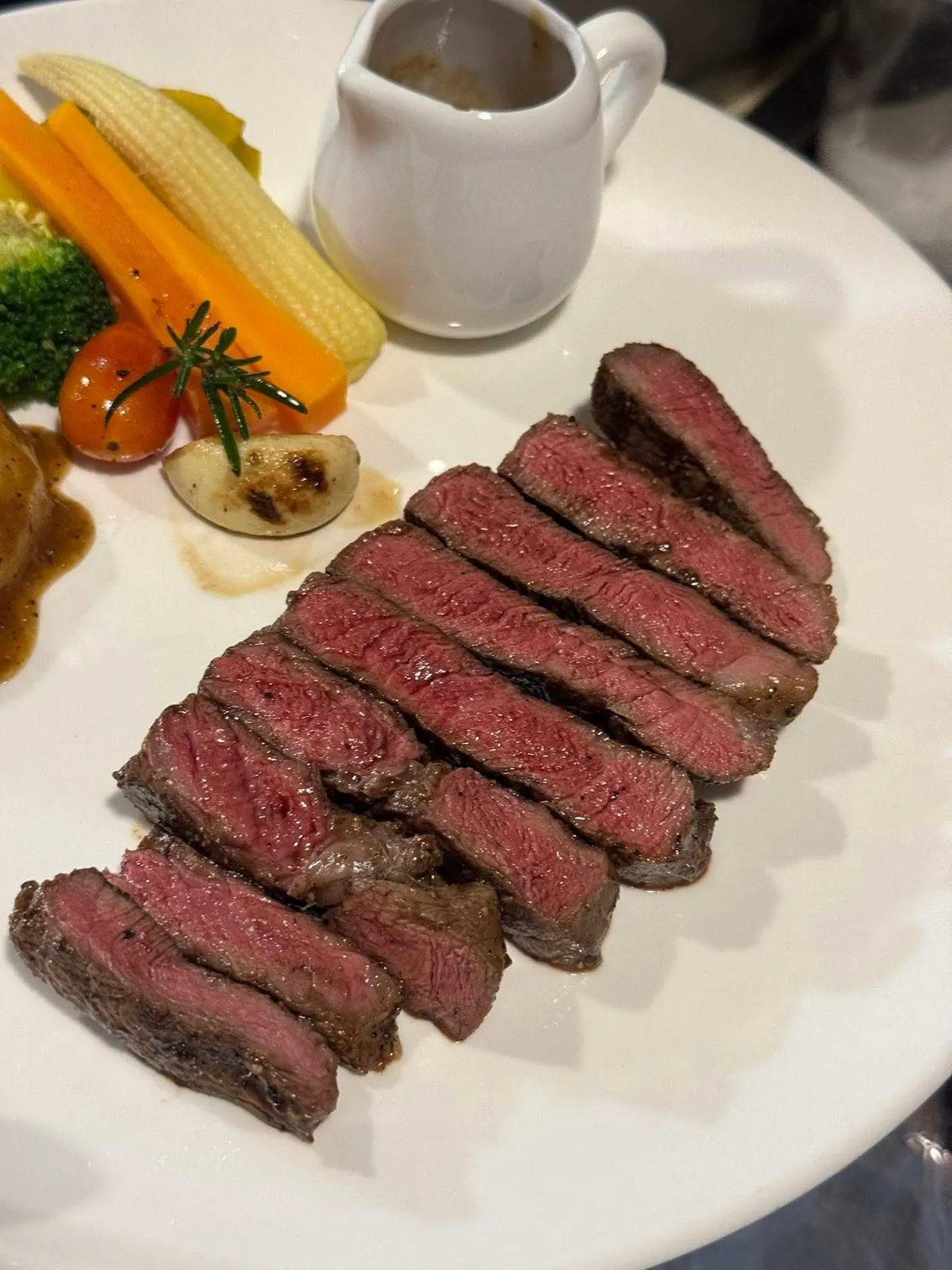เนื้อดรายเอจสไลซ์ระดับมีเดียมแรร์ บนจานขาวพร้อมน้ำเกรวี่